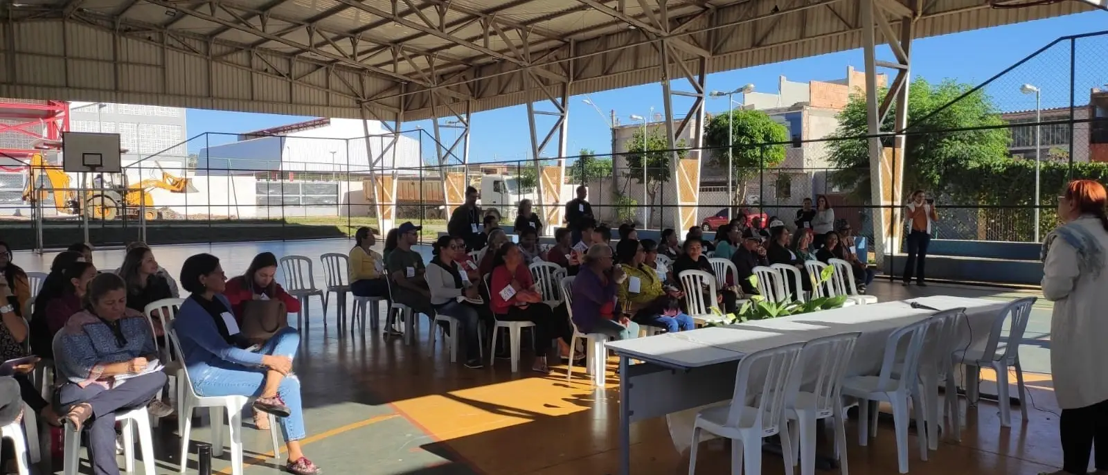 Participantes sentados em um pátio coberto durante a Conferência Livre de Assistência Social.