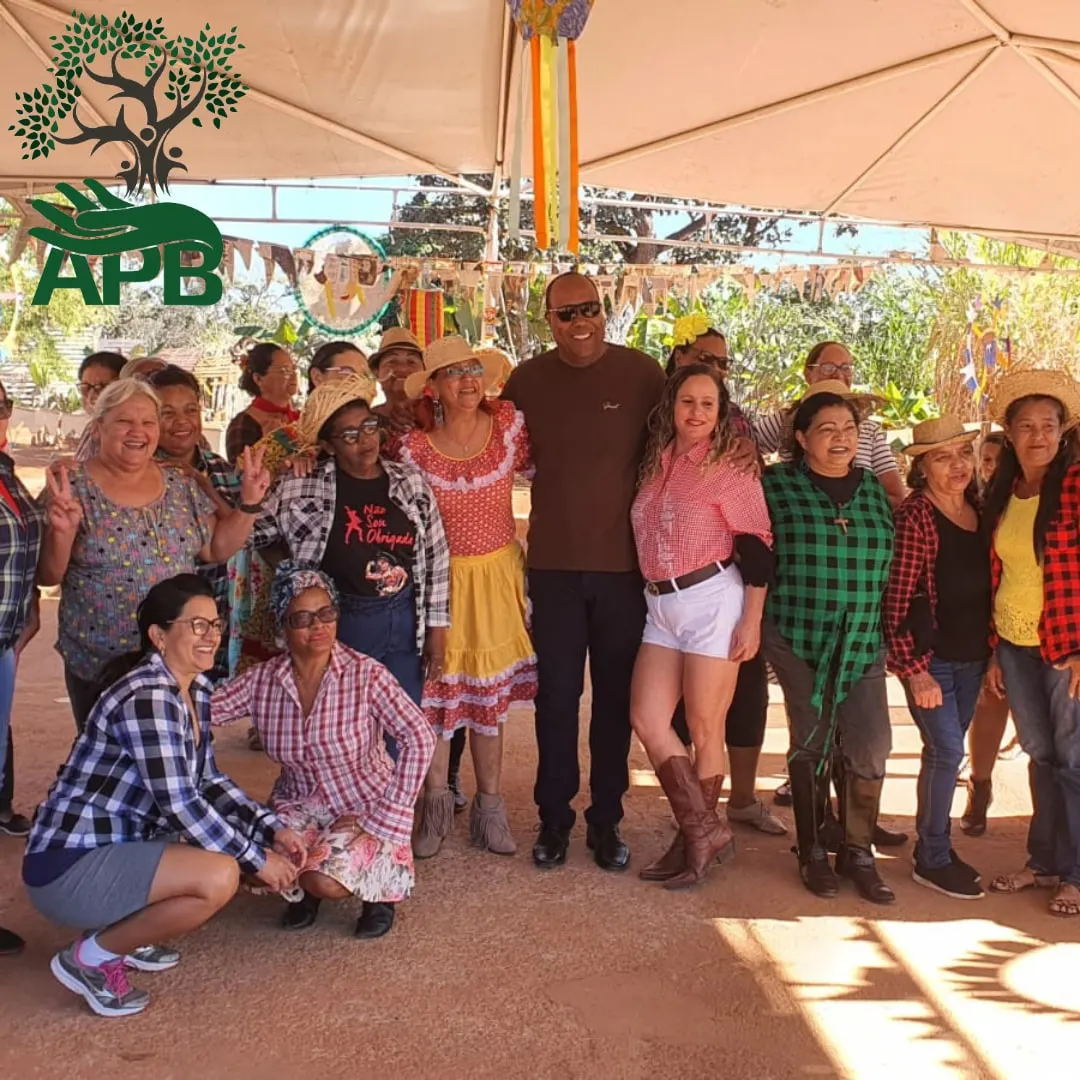 Grupo de adultos em trajes de festa junina posando sob uma tenda ao ar livre.