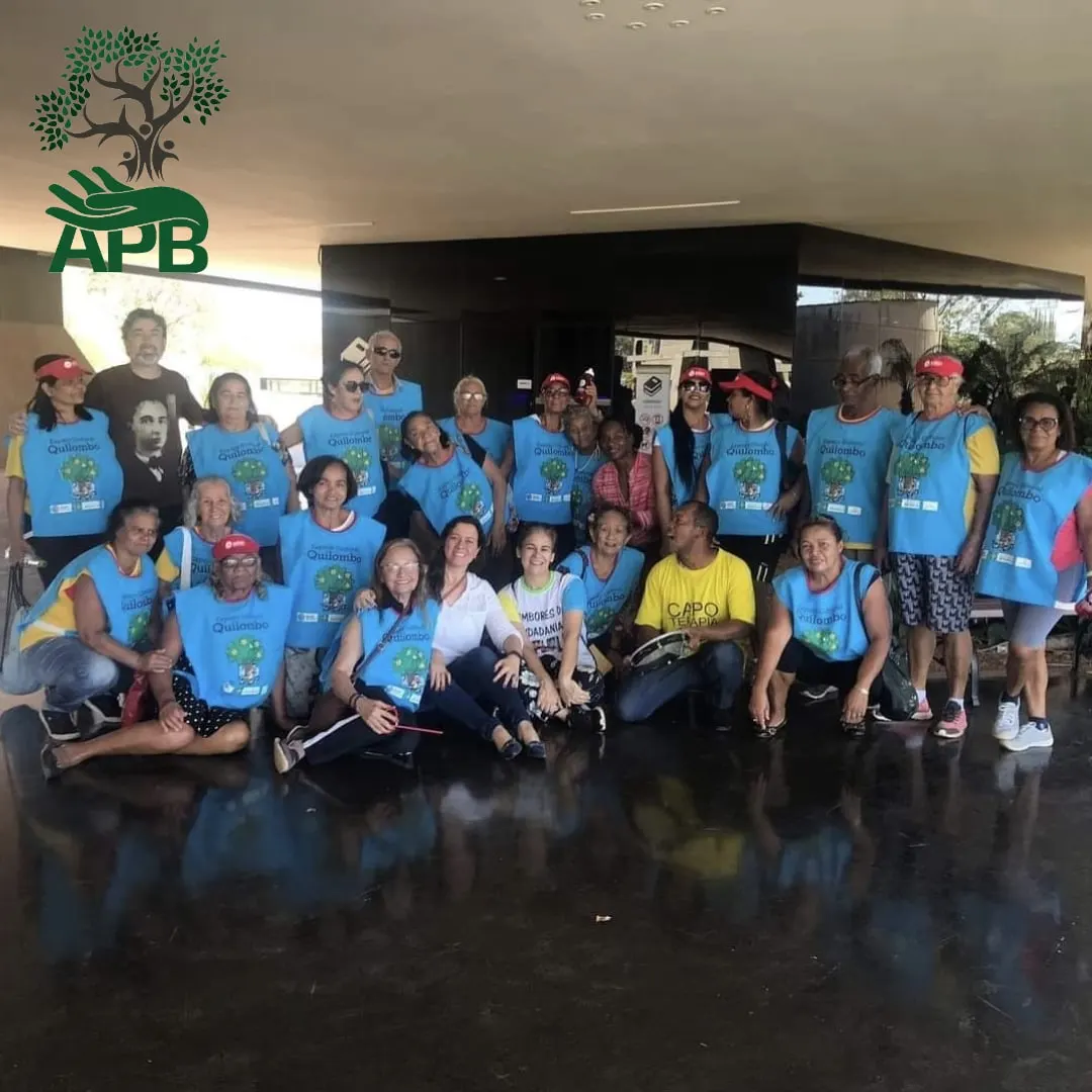 Grupo de pessoas de colete azul posando agachadas e em pé sob uma cobertura.