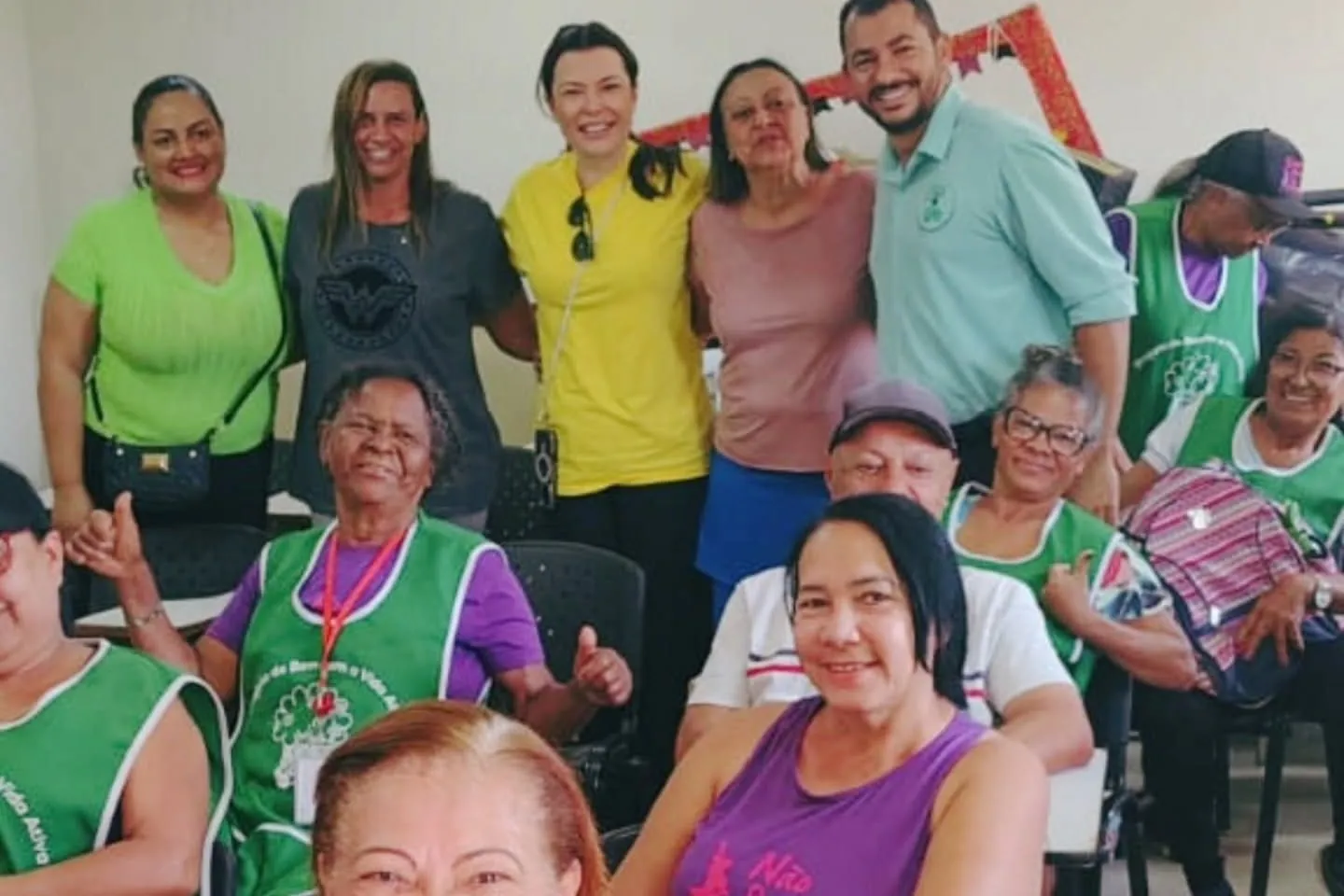 Participantes dos projetos para pessoas idosas, de colete verde, reunidas com a equipe da APB durante uma visita institucional.
