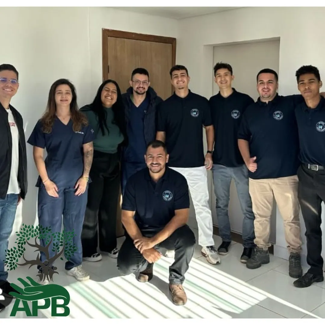 Equipe de adultos de camisa azul-marinho posando em grupo em uma sala clara.