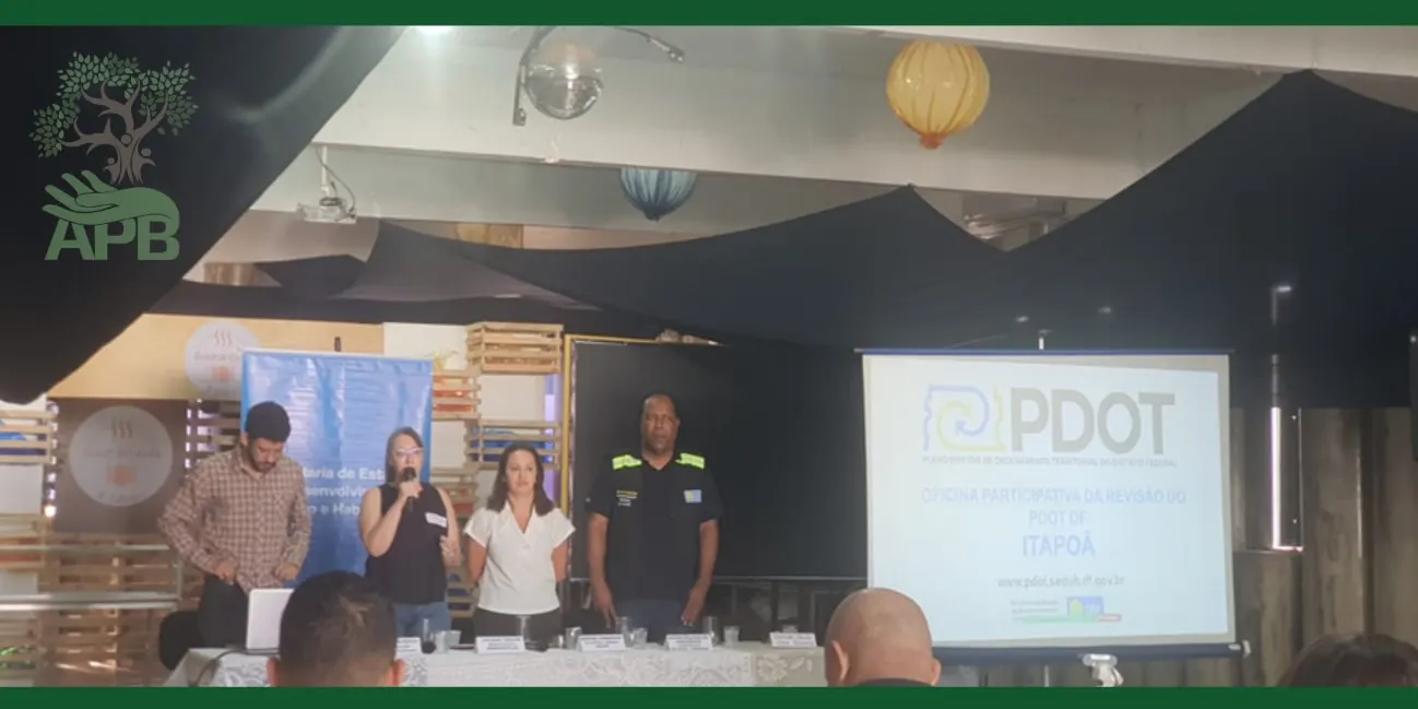 Pessoas conduzem uma reunião diante de um telão com a sigla PDOT em um espaço fechado.